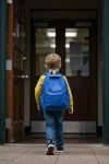 boy-with-blue-backpack-entering-school-building